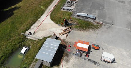 Drohnenaufnahme mit versperrtem Weg und Auto in Wassergrube